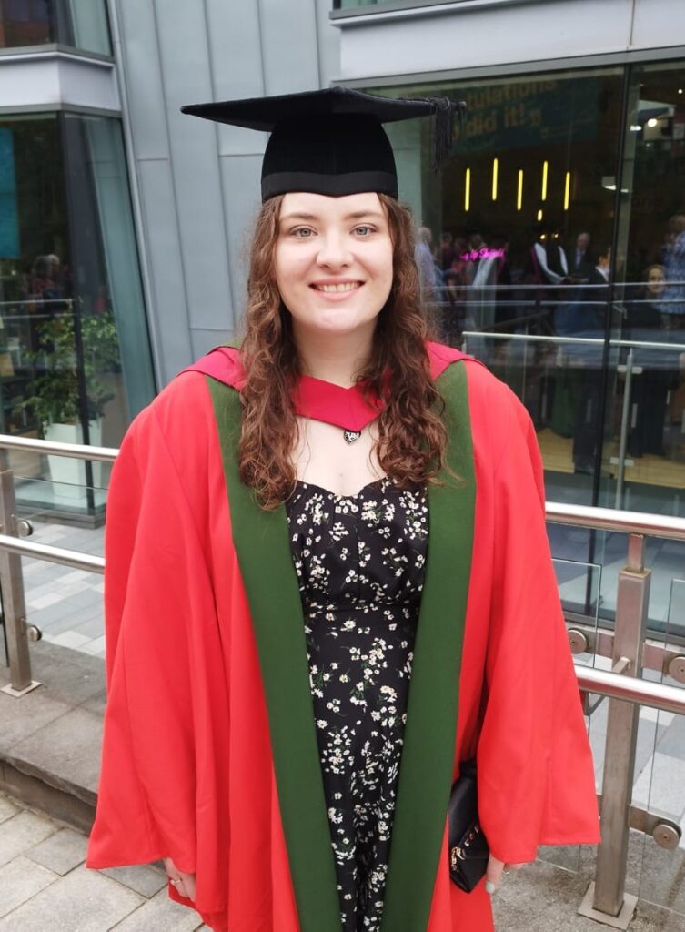A photo of Katy at her PhD graduation, wearing a cap and gown. 